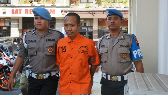 Tersangka Sujarno digelandang polisi usai ditangkap di rumahnya. (Wagino)