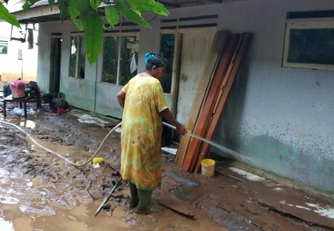 BERSIH-BERSIH: Warga membersihkan rumahnya setelah banjir menggenangi permukiman.